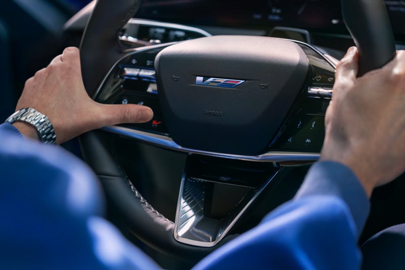 Close-up of a Man About to Press the V-Button on the 2026 OPTIQ-V Steering Wheel | Bob McCosh Cadillac in COLUMBIA MO