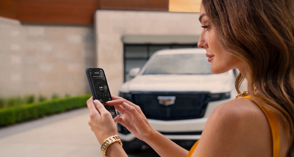lady checking her mobile with a Cadillac vehicle background | Bob McCosh Cadillac in COLUMBIA MO